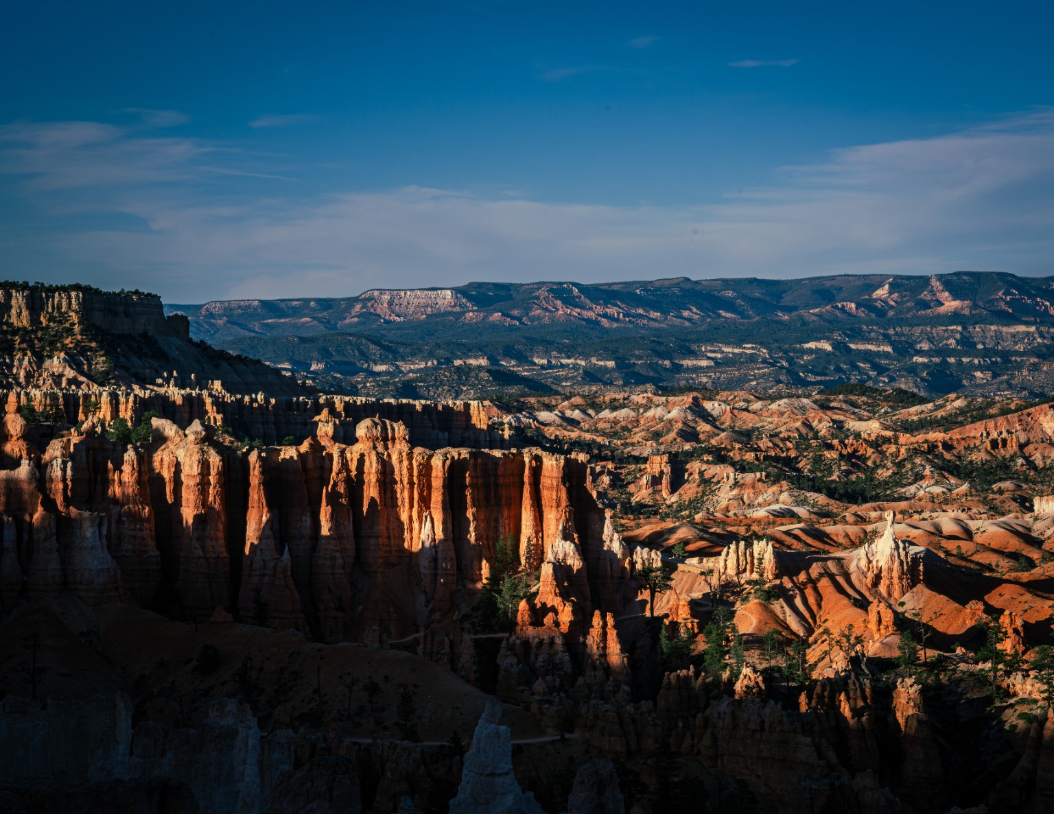 Rows of orange hoodoos rise beneath a clear sky, revealing the layers and uneven forms of the eroded plateau. Bryce Canyon National Park, Utah.