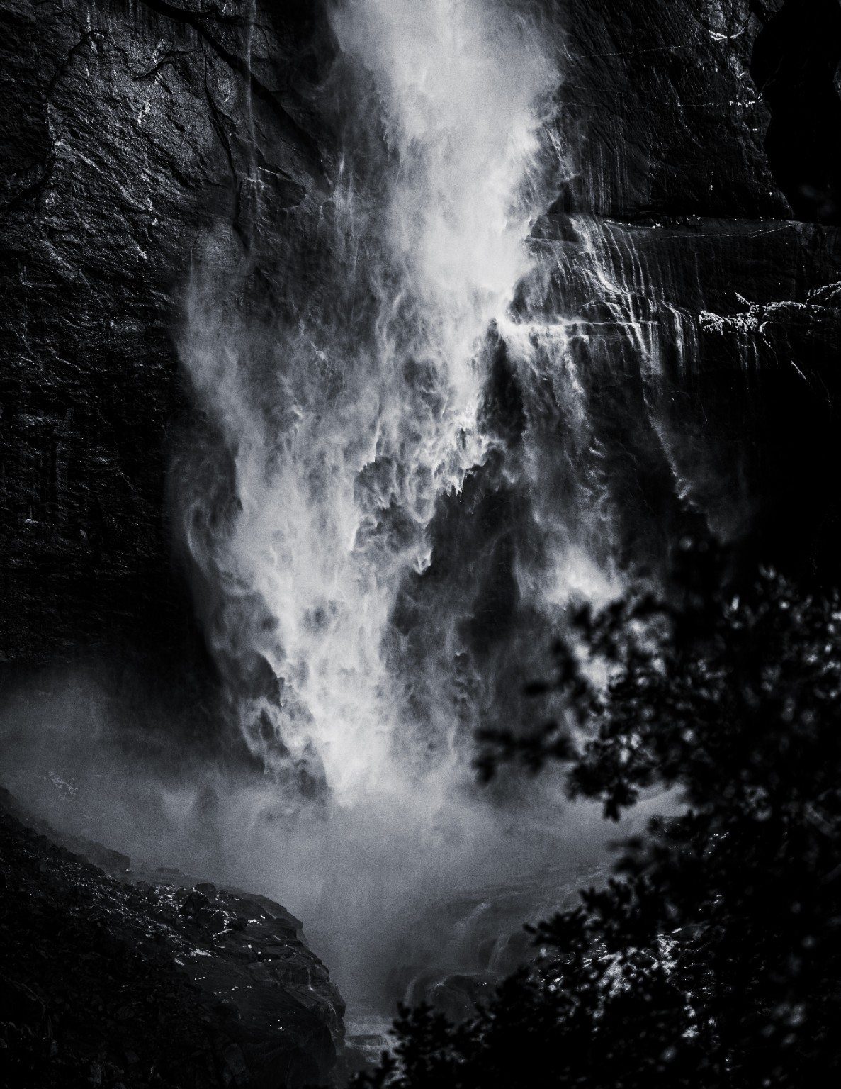 White water breaks across dark rock, its spray and cascading channels rendered in black and white. Yosemite National Park, California.
